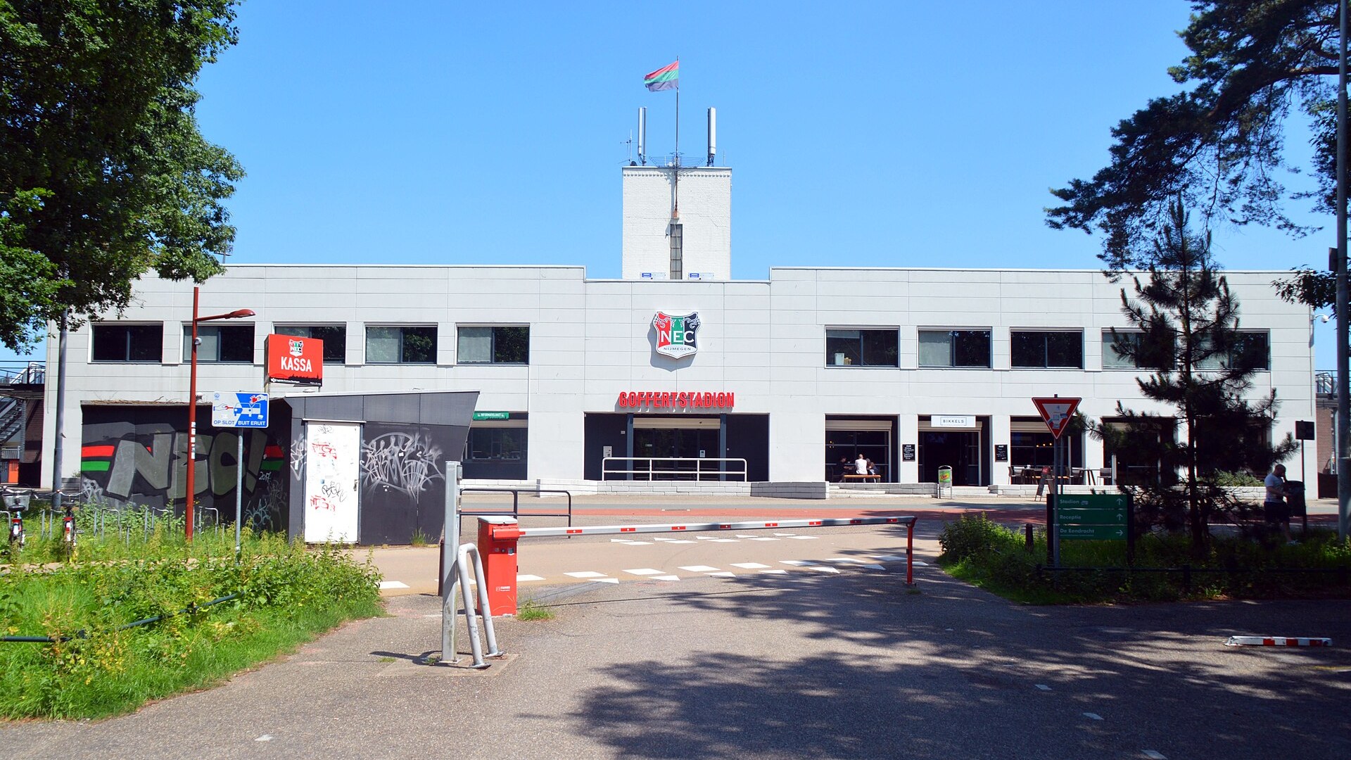Главният вход на стадион „Гоферт“ в Неймеген с логото на НЕК на фасадата в слънчев ден