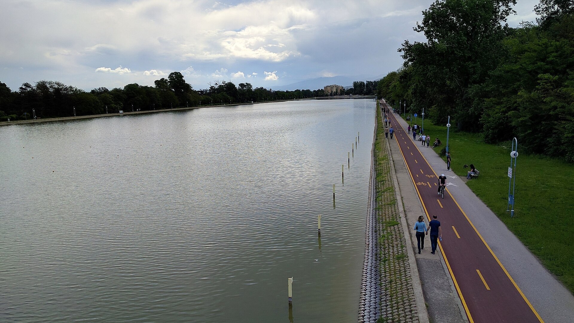 Гребният канал в Пловдив с алея и велоалея покрай водата, хора се разхождат под облачно небе